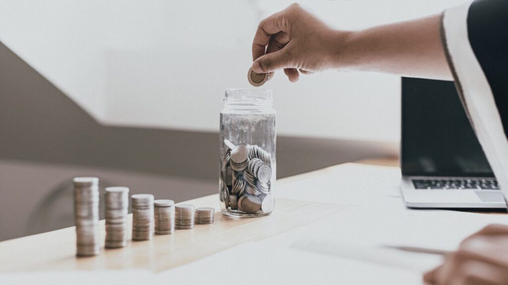 瓶にお金を入れてる人の手