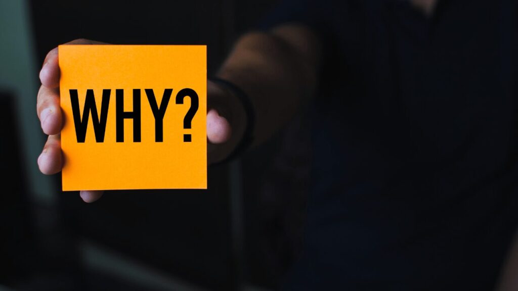 whyと書かれた紙を持ってる人の手