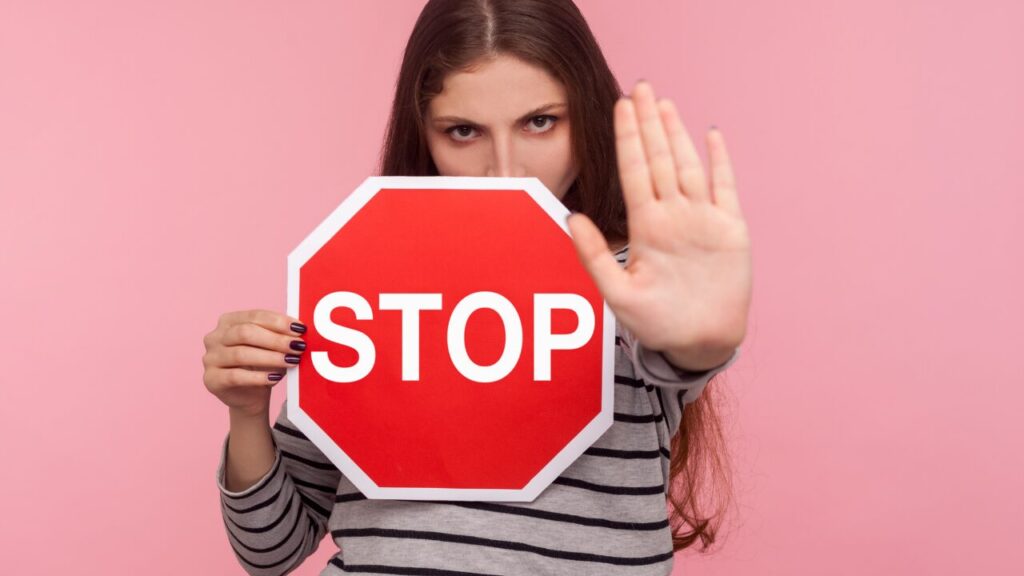 stopと書かれた標識を持ってる女性